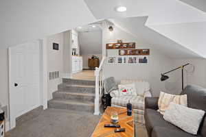 Living room featuring vaulted ceiling, stairway, and recessed lighting