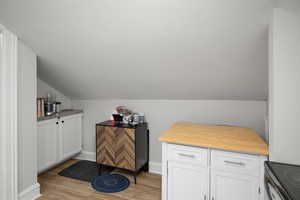 Bar with lofted ceiling, light wood-style flooring, stainless steel electric range oven, and baseboards