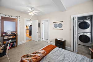 Carpeted bedroom featuring stacked washer / dryer, baseboards, freestanding refrigerator, and a ceiling fan