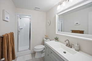 Full bath featuring toilet, vanity, and a stall shower