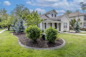 View of front of property featuring a front lawn, a chimney, stucco siding, and a porch