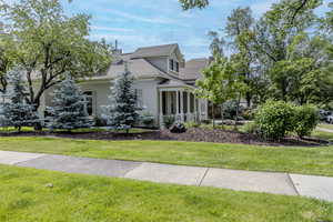View of front of home featuring stucco siding, a front lawn, roof with shingles, and a chimney