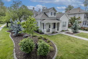 View of front of home featuring roof with shingles, covered porch, stucco siding, and a front yard