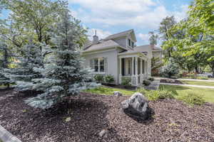View of side of property with a chimney, stucco siding, a shingled roof, and a lawn