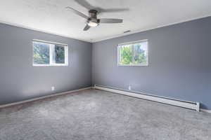 Carpeted spare room with baseboard heating, ceiling fan, crown molding, a textured ceiling, and baseboards