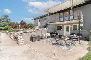 View of patio featuring an outdoor living space, stairs, and a balcony