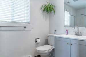 Bathroom featuring vanity, toilet, and a shower