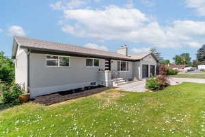 View of front of property featuring an attached garage, driveway, brick siding, a chimney, and a front yard