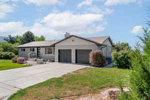 Single story home featuring a garage, concrete driveway, a front lawn, brick siding, and a chimney