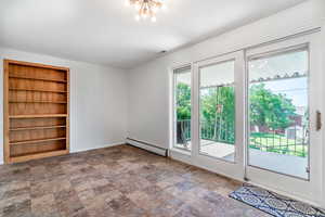 Unfurnished room with baseboard heating, built in features, stone finish floors, baseboards, and a chandelier