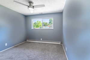 Unfurnished room with a baseboard heating unit, carpet floors, a textured ceiling, a ceiling fan, and baseboards
