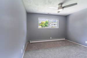 Spare room featuring a baseboard radiator, a textured ceiling, carpet, ceiling fan, and baseboards