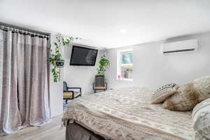 Bedroom featuring a wall mounted air conditioner, light wood-type flooring, and recessed lighting