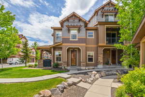 Craftsman house with a balcony, stone siding, board and batten siding, and a front lawn