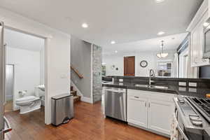 Kitchen with stainless steel appliances, a sink, white cabinets, recessed lighting, and hardwood / wood-style flooring