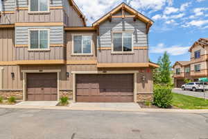 Multi unit property featuring board and batten siding, stone siding, and an attached garage