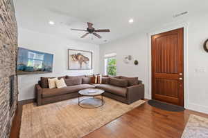 Living room with wood finished floors, ceiling fan, recessed lighting, and baseboards