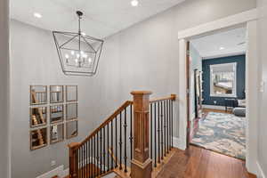 Hallway with an upstairs landing, a chandelier, recessed lighting, wood finished floors, and baseboards