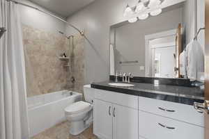 Full bath featuring shower / bathtub combination with curtain, toilet, vanity, and tile patterned floors