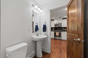 Bathroom featuring toilet, recessed lighting, wood finished floors, a sink, and baseboards