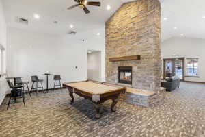 Recreation room with carpet flooring, a ceiling fan, high vaulted ceiling, pool table, and a fireplace
