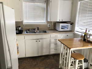 Kitchen with white appliances, a sink, light countertops, and white cabinets