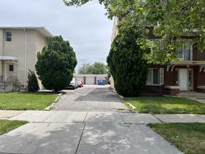 View of front of home with brick siding, a front yard, a garage, and an outbuilding