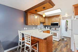 Kitchen featuring white appliances, a sink, a peninsula, light countertops, and pendant lighting