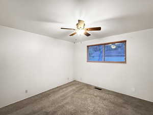 Carpeted spare room with a ceiling fan
