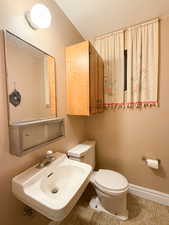 Half bath featuring a sink, toilet, baseboards, and tile patterned floors