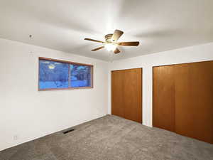 Unfurnished bedroom with carpet flooring, multiple closets, and ceiling fan