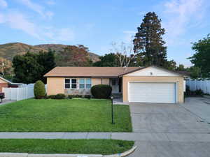 Ranch-style house with a garage, driveway, a mountain view, and brick siding