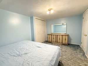 Bedroom featuring carpet, a textured ceiling, a closet, and baseboards