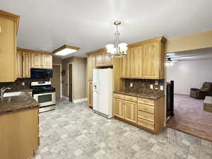 Kitchen featuring gas stove, black microwave, white refrigerator with ice dispenser, a sink, and decorative backsplash
