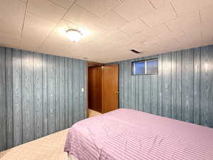 Bedroom featuring wood walls and carpet