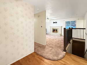 Hall with baseboards, wood finished floors, wallpapered walls, an upstairs landing, and a textured ceiling