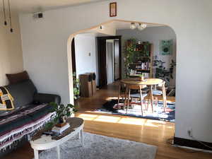 Living area featuring arched walkways and wood finished floors