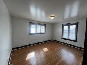 Unfurnished room with hardwood / wood-style floors, healthy amount of natural light, and baseboards