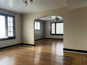 Spare room with arched walkways, wood-type flooring, ceiling fan, baseboards, and a textured ceiling