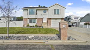 Bi-level home with brick siding, driveway, and an attached garage