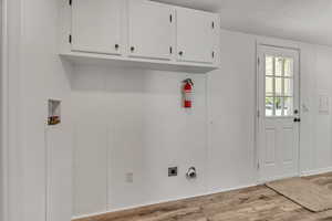 Washroom featuring wood finished floors, hookup for an electric dryer, hookup for a washing machine, cabinet space, and a textured ceiling