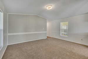 Carpeted empty room featuring lofted ceiling and a textured ceiling