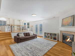 Living room featuring light wood-type flooring, a tile fireplace, a chandelier, and stairs