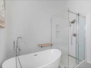 Full bath with a shower stall and a freestanding tub