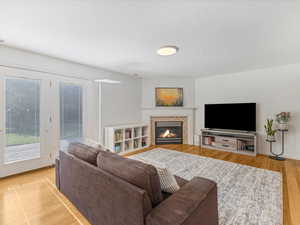 Living room with a tile fireplace, light wood-type flooring, and baseboards