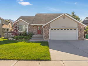 View of front of home featuring brick siding, a front lawn, an attached garage, and concrete driveway