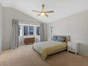 Bedroom with lofted ceiling, light colored carpet, radiator, baseboards, and ceiling fan
