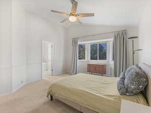 Bedroom featuring vaulted ceiling, carpet floors, baseboards, a ceiling fan, and connected bathroom