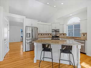Kitchen featuring appliances with stainless steel finishes, a sink, under cabinet range hood, a kitchen island, and a kitchen bar