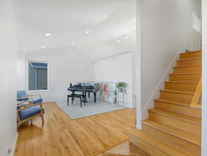 Foyer with stairway, lofted ceiling, wood finished floors, baseboards, and recessed lighting